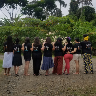 Nine members of the Whose Knowledge? team stand next to each other in the rainforest during a retreat in Costa Rica.