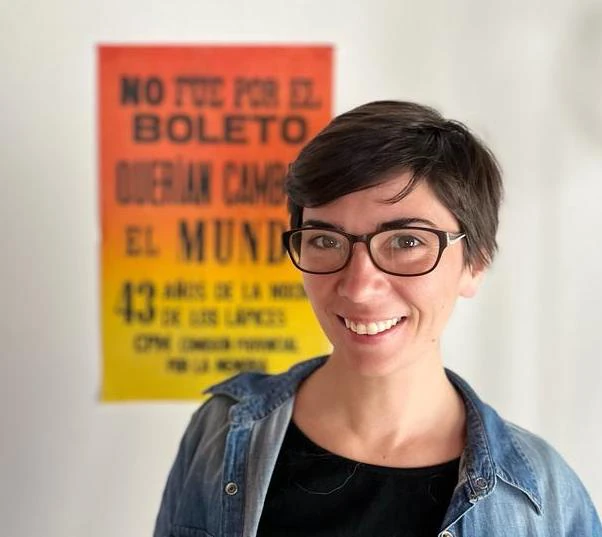 Constanza Verón wears black-rimmed glasses smiles widely looking into the camera.