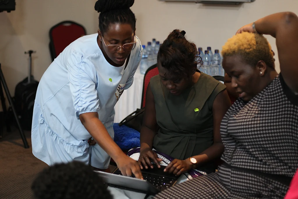 Three African women in the digital rights and safety sphere look at a laptop intently.