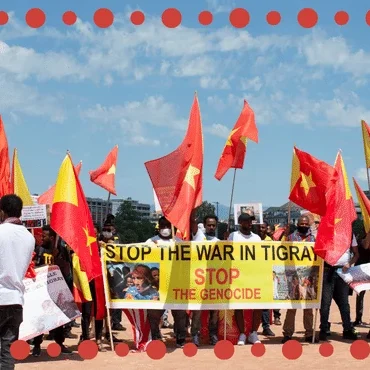 Protesters wave red and yellow flags at a demonstration about the genocide in Tigray.